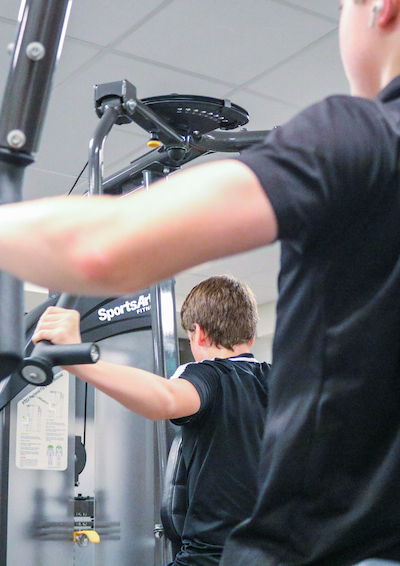 En dreng, der træner på en maskine i fitnesscenter